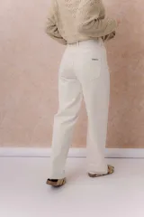 Pantalón de jean de tiro medio-alto y pierna amplia con caída recta, color amarillo manteca, con diseño clásico de cinco bolsillos y cierre delantero con botón.