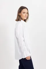 Camisa blanca de algodón con cuello mao, cierre frontal oculto y mangas largas fruncidas con volumen.