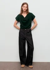 Jersey de punto fino color verde oscuro, con cuello drapeado y manga corta. Presenta un diseño recto y holgado.