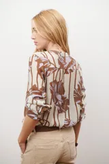 Camisa de manga larga con estampado floral en tonos marrones y negros, cuello mao y cierre frontal parcial con botones.