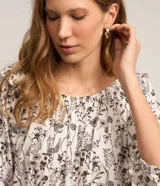 Blusa blanca con estampado floral negro, escote hombro a hombro y mangas 3/4 abullonadas.