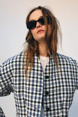 Chaqueta corta de Zara Woman Collection confeccionada en tejido de algodón con estampado de cuadros en tonos blanco, azul y negro. Presenta escote en pico, manga larga y cierre frontal con botones oscuros.