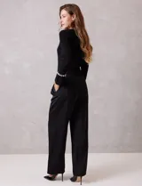 Pantalón palazzo de satén color negro, de tiro alto con pretina delantera estructurada, pasadores para cinturón y bolsillos laterales. Presenta una caída fluida y amplia, con elástico en la parte posterior de la cintura para mayor ajuste.