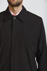 Gabardina de corte recto y estilo minimalista, color azul marino, con cuello camisero, cierre frontal oculto por solapa y puños ajustables con botón.