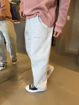 Pantalón deportivo de corte baggy y estilo oversize, confeccionado en algodón color gris melange. Presenta costuras verticales decorativas en el frente, bolsillos laterales y un pequeño bordado en la zona del muslo.