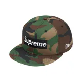Gorra tipo snapback de Supreme en colaboración con New Era, con estampado de camuflaje y parche rectangular negro con el logo de la marca en blanco en la parte frontal.