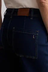 Jean culotte de tiro alto y corte recto, confeccionado en denim de color azul oscuro. Presenta costuras en contraste y un diseño de pierna ancha con ruedo desflecado.