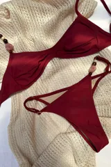 Conjunto de bikini bordeaux con corpiño triangular con detalle de cuentas en los breteles y bombacha semivedetina regulable con detalle de cuentas en uno de los breteles laterales.