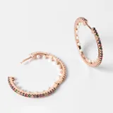 Aros tipo argolla de acero con baño de oro rosa de 18k, con cristales de colores en el exterior y perlas en el interior.