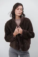 Chaqueta tipo gamulán de color marrón, con solapas amplias forradas en corderito sintético oscuro. Presenta un diseño cruzado con botones frontales y mangas largas, ideal para un estilo invernal.