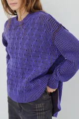 Buzo reversible de tejido de punto con diseño de trenzas, cuello redondo y mangas largas. Presenta una combinación de colores en contraste, con un lado en violeta y el otro en marrón oscuro.