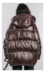 Campera oversize color marrón brillante con capucha, cierre frontal de doble cursor y bolsillos laterales con cremallera. Tiene relleno natural y ajuste inferior con cordón.