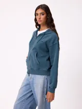 Canguro con cierre frontal y capucha, color gris con efecto desgastado. Presenta bolsillos laterales y logo bordado en el pecho.