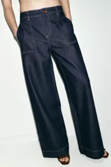 Jeans de tiro medio con corte wide leg y pernera ancha. Presenta bolsillos de plastrón en el delantero y cierre frontal con cremallera y botón.