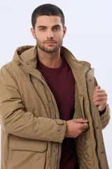 Campera de abrigo color beige con capucha desmontable, cierre frontal con botones a presión y cremallera. Presenta bolsillos frontales con solapa, interior parcialmente forrado en corderito y acolchado en la parte inferior.