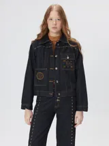 Campera denim crop de mezclilla oscura, con apliques metálicos en el pecho, bolsillos delanteros cruzados con detalles bordados y de parches.