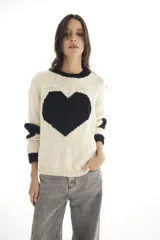 Sweater de lana merino color blanco marfil con un gran corazón negro en el frente, cuello redondo y mangas largas con puños acanalados negros.