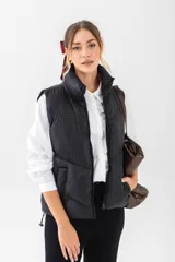 Chaleco puffer negro con cuello alto, cierre frontal y bolsillos laterales.