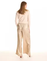 Pantalón wide leg de tela laminada metalizada color blanco, con pretina elástica y lazo de ajuste en la cintura. Cuenta con bolsillos laterales.