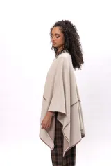 Ruana de algodón en color beige con detalles de costura decorativa en contraste color marrón. Presenta un diseño abierto con caída fluida y mangas tipo capa.