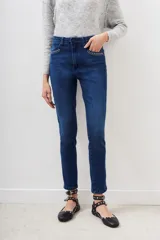 Jean de denim azul oscuro con lavado localizado, corte slim (delgado y estrecho) y tiro medio. Presenta apliques de hot fix (pequeños tachas plateadas) en la boca de los bolsillos delanteros.