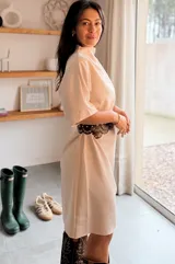 Vestido corto de corte recto y mangas cortas, confeccionado en tela lisa. Incluye un cinturón decorativo de cuero con ojales metálicos circulares que se repiten en todo su diseño.
