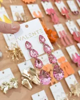 Aros colgantes largos compuestos por cuatro cristales facetados en forma de gota de color rosado, engarzados en metal dorado.