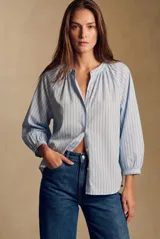 Blusa oversize celeste a rayas con cuello mao, escote en V y mangas 3/4 abullonadas con puños elásticos.