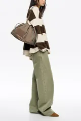 Bolso de hombro Bimba y Lola de tamaño grande, confeccionado en nylon negro con estructura blanda. Presenta dos asas largas, cierre superior y detalles de cordones laterales en tonos tierra. Incluye un parche frontal con el logo de la marca grabado.