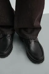 Zapato náutico de piel color negro, con cordones y suela dentada tipo track.