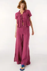 Blusa de lino color azul, de corte cropped y manga corta. Presenta cuello camisero, diseño con tablas frontales y cierre mediante lazos delgados en el centro.