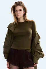 Remera en punto acanalado fino, de color verde militar, con cuello redondo fino ribeteado y manga corta al codo. Modelo entallado.