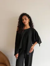 Blusa de tejido waffle color marrón, con diseño asimétrico de un solo hombro y mangas anchas tipo capa.