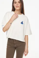 Remera de algodón con elastano, de moldería boxy y calce relajado, color blanco. Presenta un bordado exclusivo de un atardecer en tonos azules en el pecho.