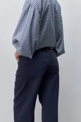 Pantalón jean de tiro alto con calce straight y pierna recta, confeccionado en denim de aspecto limpio. Cuenta con cinco bolsillos, cierre frontal con botón y presillas para cinturón.