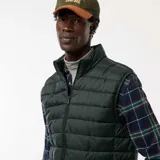 Chaleco tipo puffer de color verde oscuro, con cierre frontal completo, cuello alto y diseño acolchado horizontal.