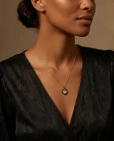 Collar de acero con baño de oro, compuesto por una cadena fina y un dije en forma de corazón que combina cerámica negra y circonias brillantes.