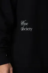 Buzo de cuello redondo y corte oversize, confeccionado en frisa suave. Presenta un diseño minimalista en color negro con un pequeño logo ovalado en el centro del pecho y una estampa sutil en el lateral inferior derecho.