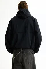 Campera rompevientos de nylon color negro, repelente al agua, con capucha ajustable con cordón, cierre frontal y bolsillos laterales. Cuenta con elásticos en los puños y forro interno.