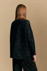Sobrecamisa de efecto engomado en color negro, con textura lavada, cuello clásico, cierre frontal con botones a tono y bolsillos frontales con solapa.