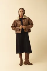 Campera de cuero color suela con cuello de corderito sintético en tono crema. Presenta cierre frontal con botones grandes de carey y bolsillos frontales tipo parche.