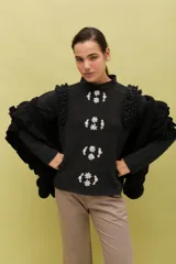 Chal de lana color marrón con diseño envolvente, decorado con volados aplicados en toda la superficie que aportan textura y movimiento.