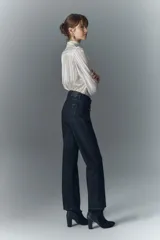 Jean de tiro alto, color negro, con corte acampanado y pequeños apliques brillantes distribuidos por toda la tela.