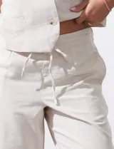 Pantalón crop de corte recto y estilo casual, confeccionado en una mezcla de fibras naturales y sintéticas. Presenta pretina trasera elastizada con lazo de ajuste frontal y bolsillos laterales verticales.