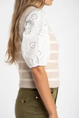 Chaleco de punto sin mangas con diseño de rayas horizontales en tonos beige y blanco, cuello redondo y terminaciones acanaladas.