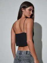 Top negro de tirantes finos con escote drapeado y detalle de pequeños brillos distribuidos en la prenda, diseño corto tipo crop top.
