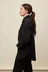 Sobrecamisa de denim de calce amplio y color azul, con cuello clásico, cierre frontal con broches metálicos y bolsillos delanteros con solapa.