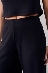 Pantalón negro de corte ancho, tiro alto y textura suave.