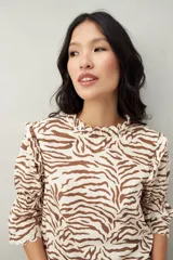 Blusa color beige con estampado abstracto en blanco, corte relajado, mangas 3/4 fruncidas y cuello con volados.