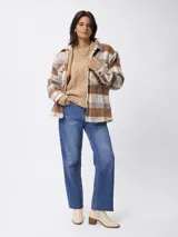 Sobrecamisa de estilo leñador con estampado de cuadros en tonos marrones, beige y gris. Presenta cuello clásico, cierre frontal con botones, bolsillos delanteros y puños tejidos acanalados. El interior está forrado con tejido tipo sherpa para mayor abrigo.
